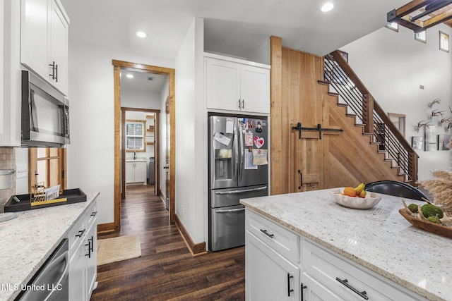 kitchen with stainless steel appliances, dark wood-type flooring, white cabinetry, and light stone countertops