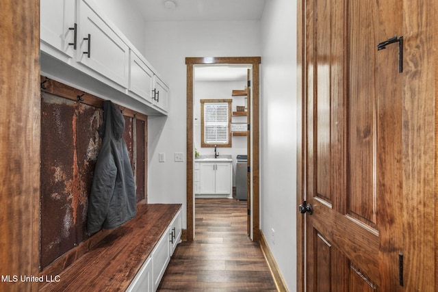 mudroom featuring dark wood-type flooring, a sink, and baseboards