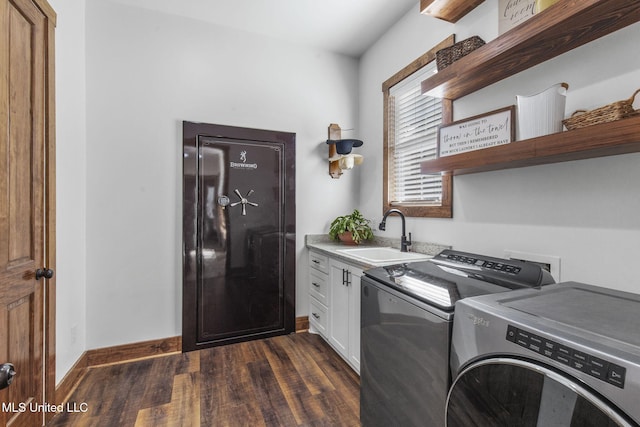 laundry area with dark wood-style floors, washing machine and clothes dryer, cabinet space, a sink, and baseboards