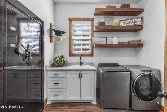 washroom with dark wood finished floors, washing machine and dryer, a sink, and cabinet space