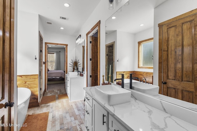 bathroom featuring visible vents, a wainscoted wall, ensuite bathroom, vanity, and a freestanding tub