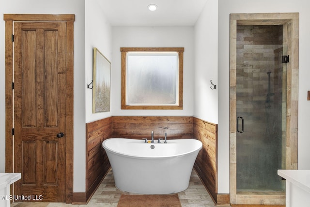 bathroom featuring a freestanding tub, a shower stall, and wainscoting