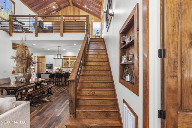 staircase with high vaulted ceiling, wood finished floors, and visible vents