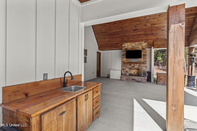 interior space featuring lofted ceiling, wood counters, concrete floors, a fireplace, and a sink