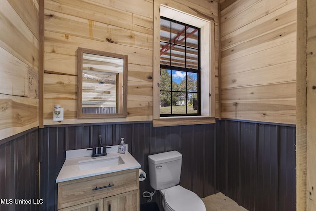 bathroom with wood walls, wainscoting, vanity, and toilet