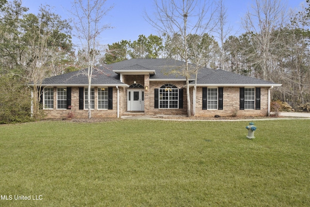 view of front of house with a front yard, brick siding, and roof with shingles