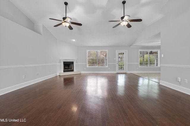 unfurnished living room with a fireplace with raised hearth, plenty of natural light, baseboards, and wood finished floors