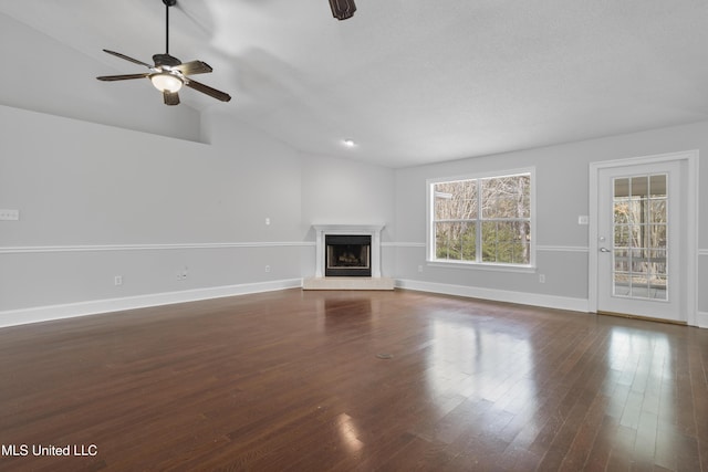 unfurnished living room featuring a fireplace with raised hearth, ceiling fan, vaulted ceiling, and wood finished floors