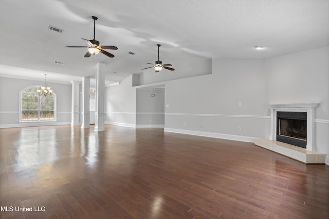 unfurnished living room with visible vents, a fireplace with raised hearth, wood finished floors, vaulted ceiling, and a textured ceiling