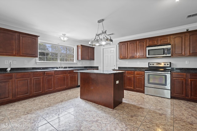 kitchen with a center island, crown molding, stainless steel appliances, dark countertops, and visible vents