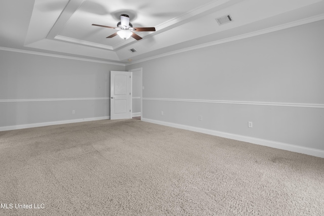 empty room featuring baseboards, visible vents, ceiling fan, a tray ceiling, and crown molding