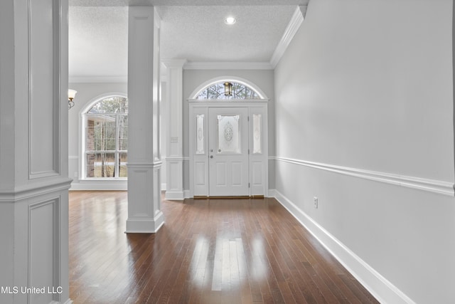 entryway featuring hardwood / wood-style flooring, ornate columns, a textured ceiling, and crown molding