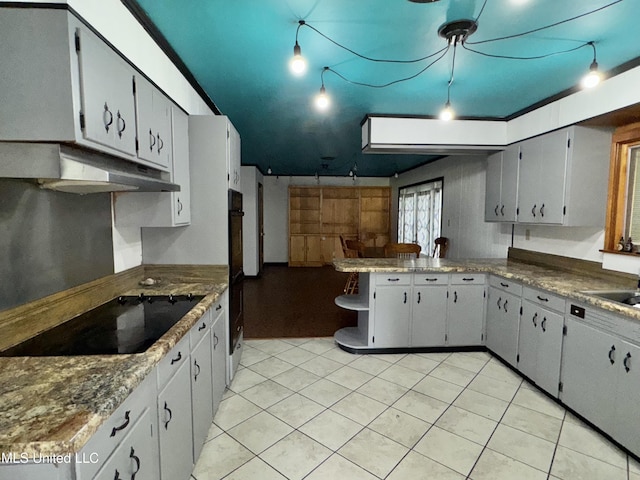 305 N Heard St, Senatobia, MS 38668 - kitchen with under cabinet range hood, black appliances, a peninsula, and light tile patterned floors