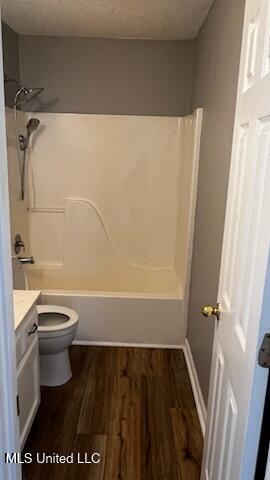 full bathroom with hardwood / wood-style flooring, vanity,  shower combination, and toilet