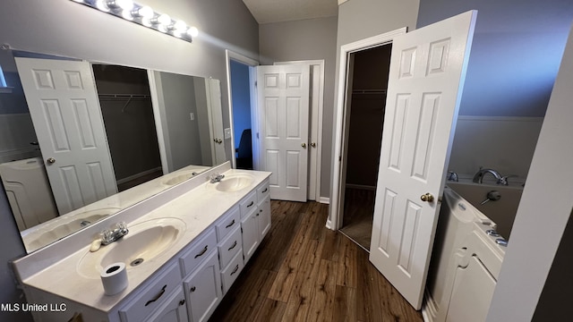 bathroom featuring hardwood / wood-style flooring, vanity, and a tub to relax in