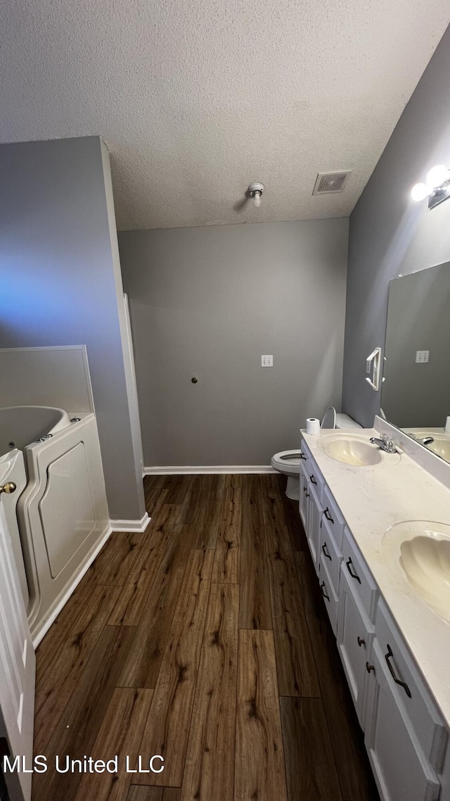 bathroom featuring vanity, hardwood / wood-style floors, a textured ceiling, and a bathing tub