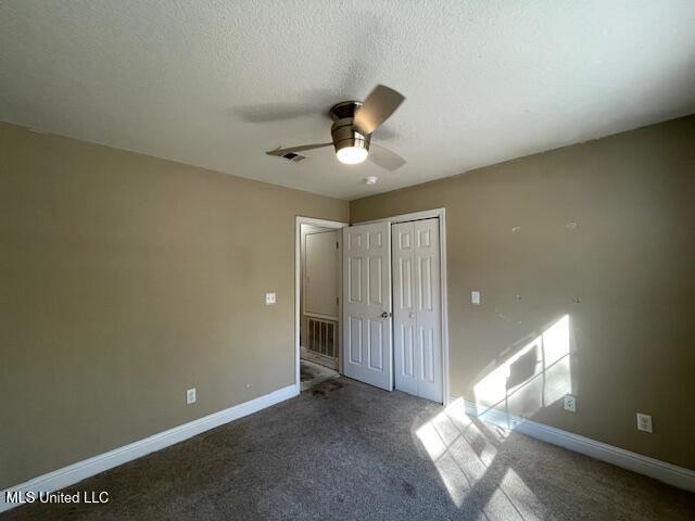 unfurnished bedroom featuring ceiling fan, a closet, carpet, and a textured ceiling