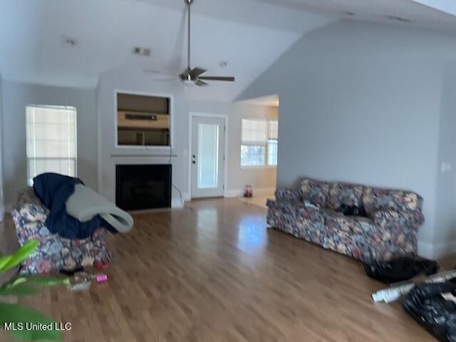 living room with wood-type flooring, vaulted ceiling, and ceiling fan