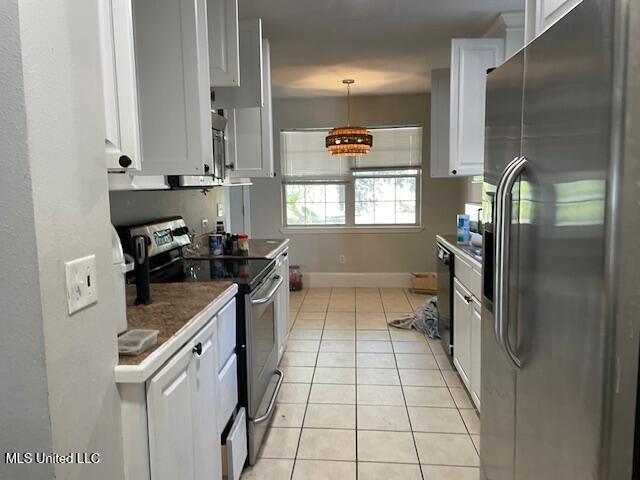 kitchen featuring light tile patterned flooring, stainless steel appliances, decorative light fixtures, and white cabinets