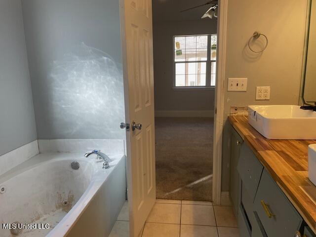 bathroom featuring ceiling fan, tile patterned floors, a bathing tub, and vanity