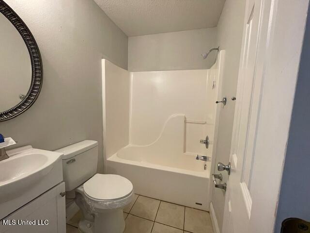 full bathroom featuring a textured ceiling, vanity, toilet, tile patterned floors, and washtub / shower combination