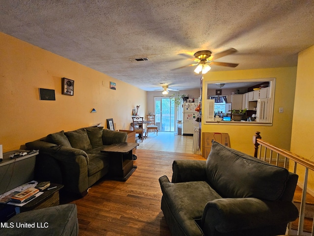 living room featuring a textured ceiling, hardwood / wood-style flooring, and ceiling fan