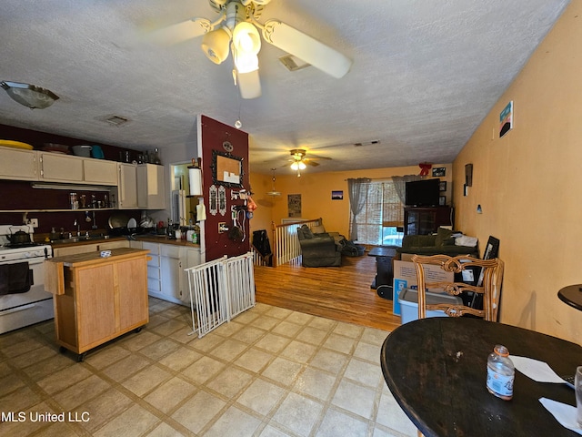 kitchen featuring sink, a textured ceiling, white gas range, light hardwood / wood-style floors, and ceiling fan