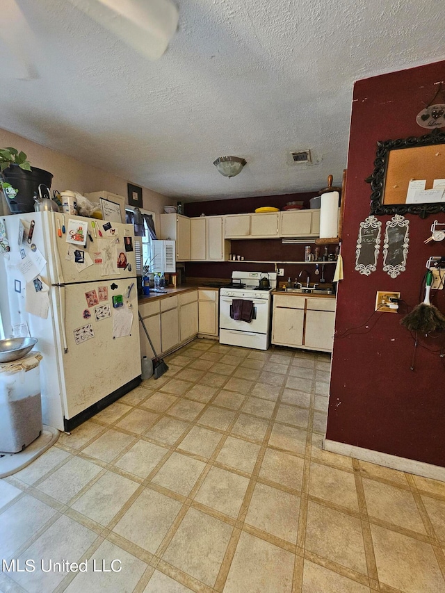 kitchen featuring white appliances, cream cabinets, a textured ceiling, and sink