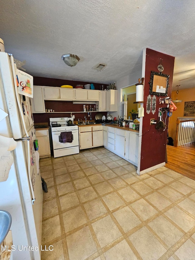 kitchen featuring white cabinetry, a textured ceiling, sink, and white appliances