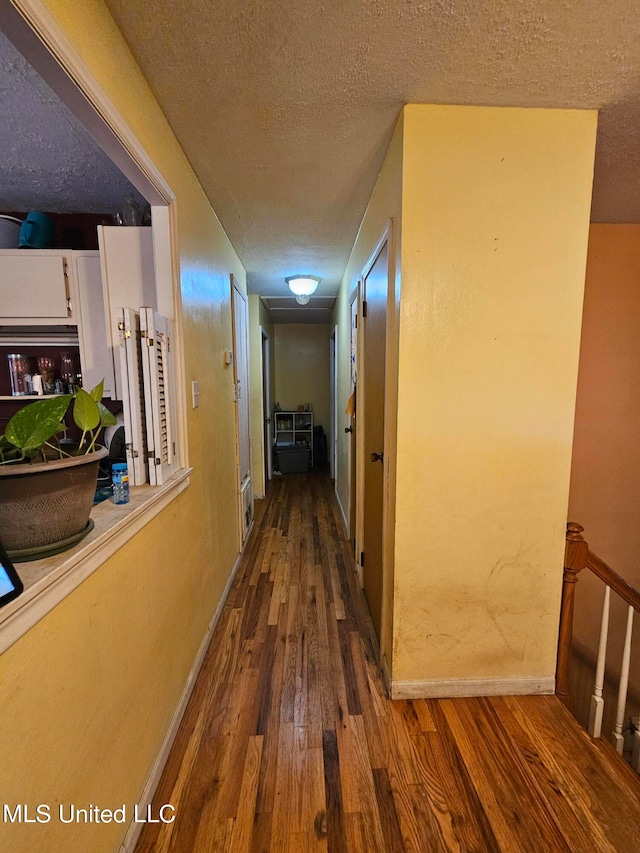 hall with hardwood / wood-style floors and a textured ceiling