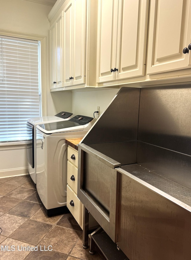 clothes washing area with cabinets and washer and clothes dryer