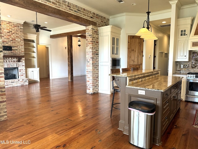 kitchen featuring a kitchen breakfast bar, dark hardwood / wood-style flooring, stainless steel range oven, and decorative light fixtures