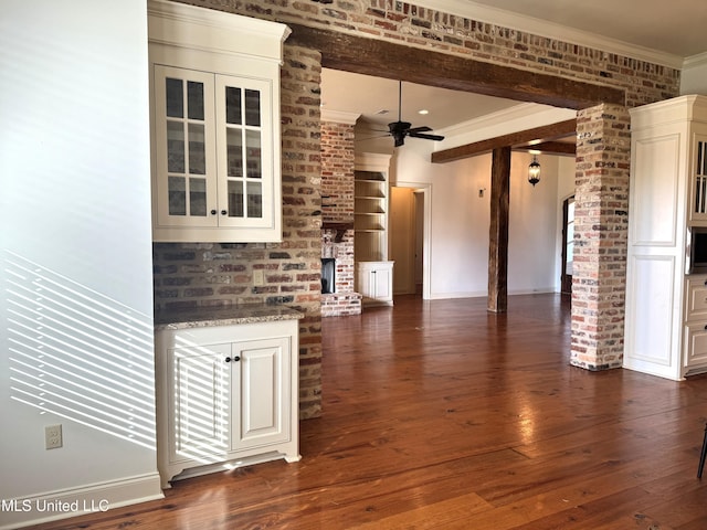 unfurnished living room featuring ceiling fan, dark hardwood / wood-style floors, brick wall, and crown molding