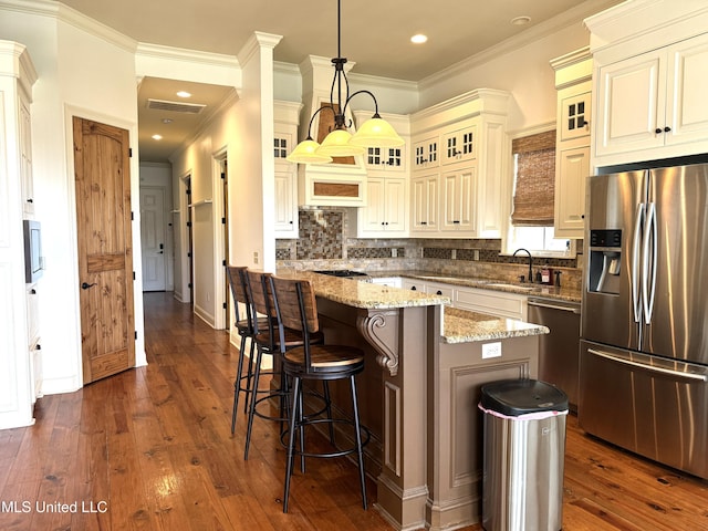kitchen featuring stainless steel appliances, hanging light fixtures, a kitchen island, and dark hardwood / wood-style flooring