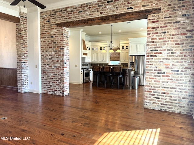 living room with dark wood-type flooring, brick wall, crown molding, and ceiling fan