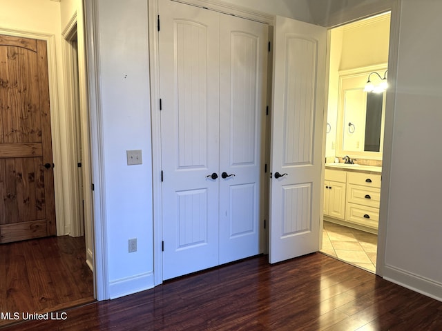 unfurnished bedroom with dark wood-type flooring, a closet, sink, and ensuite bathroom