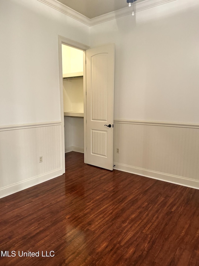 empty room with dark hardwood / wood-style flooring and crown molding