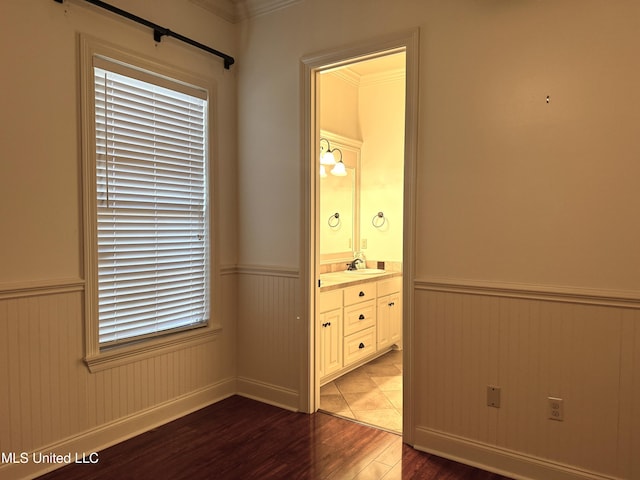unfurnished bedroom featuring hardwood / wood-style floors, ensuite bath, sink, and crown molding