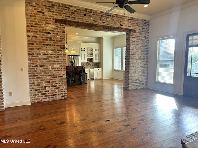living room featuring ornamental molding, brick wall, dark hardwood / wood-style floors, and ceiling fan