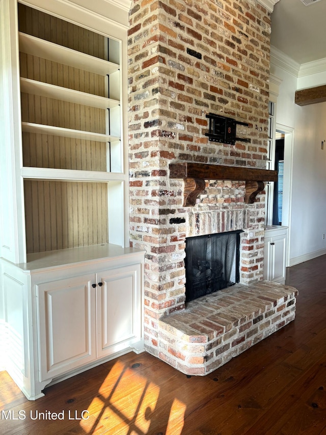 unfurnished living room featuring ornamental molding, a brick fireplace, and dark hardwood / wood-style flooring