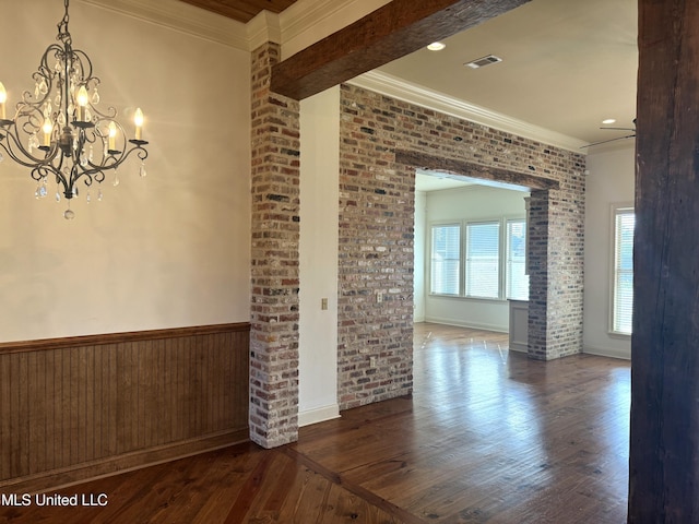 empty room featuring brick wall, dark hardwood / wood-style floors, and crown molding