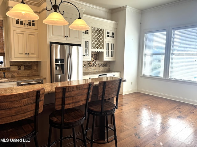 kitchen featuring stainless steel appliances, dark stone counters, hanging light fixtures, decorative backsplash, and dark wood-type flooring