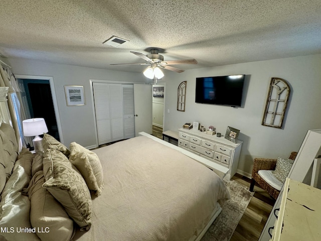 bedroom with visible vents, ceiling fan, wood finished floors, a textured ceiling, and a closet