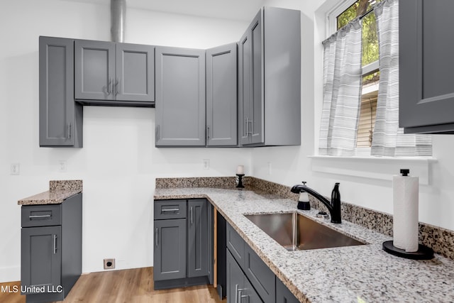 kitchen featuring a sink, light stone countertops, and gray cabinets