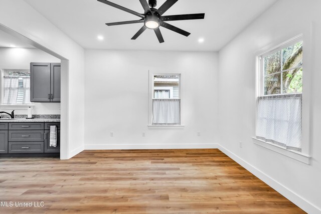 unfurnished dining area with plenty of natural light, a sink, a ceiling fan, light wood finished floors, and recessed lighting