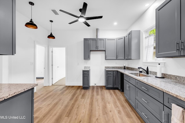 kitchen featuring a sink, gray cabinets, light wood-style floors, ceiling fan, and decorative light fixtures