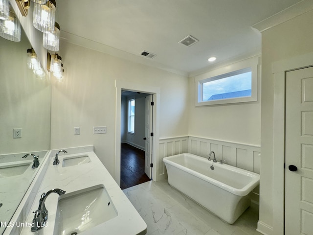 bathroom with hardwood / wood-style floors, vanity, crown molding, and a bathing tub