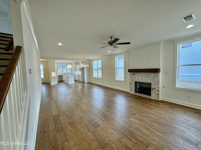 unfurnished living room featuring a fireplace, wood-type flooring, and ceiling fan with notable chandelier