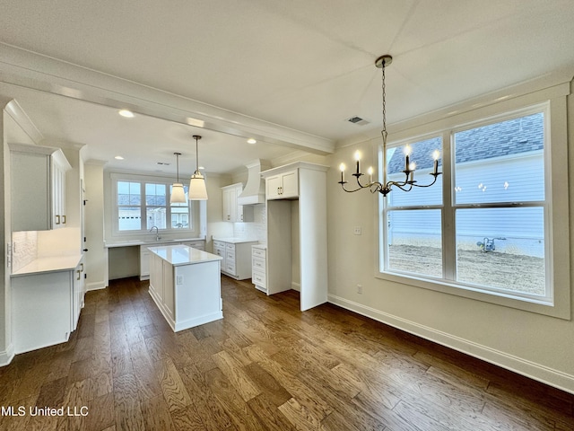 kitchen with a kitchen island, sink, dark hardwood / wood-style floors, white cabinetry, and hanging light fixtures