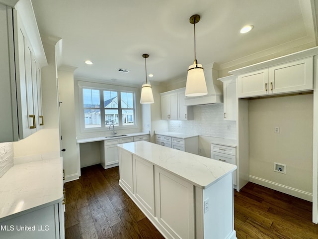 kitchen with white cabinetry, sink, light stone countertops, dark hardwood / wood-style floors, and decorative light fixtures